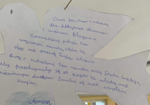 Na zdjęciu znajduje się biały gołąb wykonany z papieru, na nim widnieje modlitwa w intencji pokoju na Ukrainie.